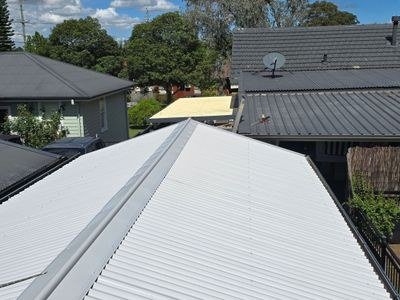 Fresh sand-and-cement bedding being laid under ridgecaps on a tile roof