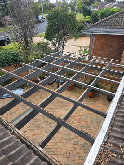 New clear polycarbonate sheets being fitted to a backyard pergola frame